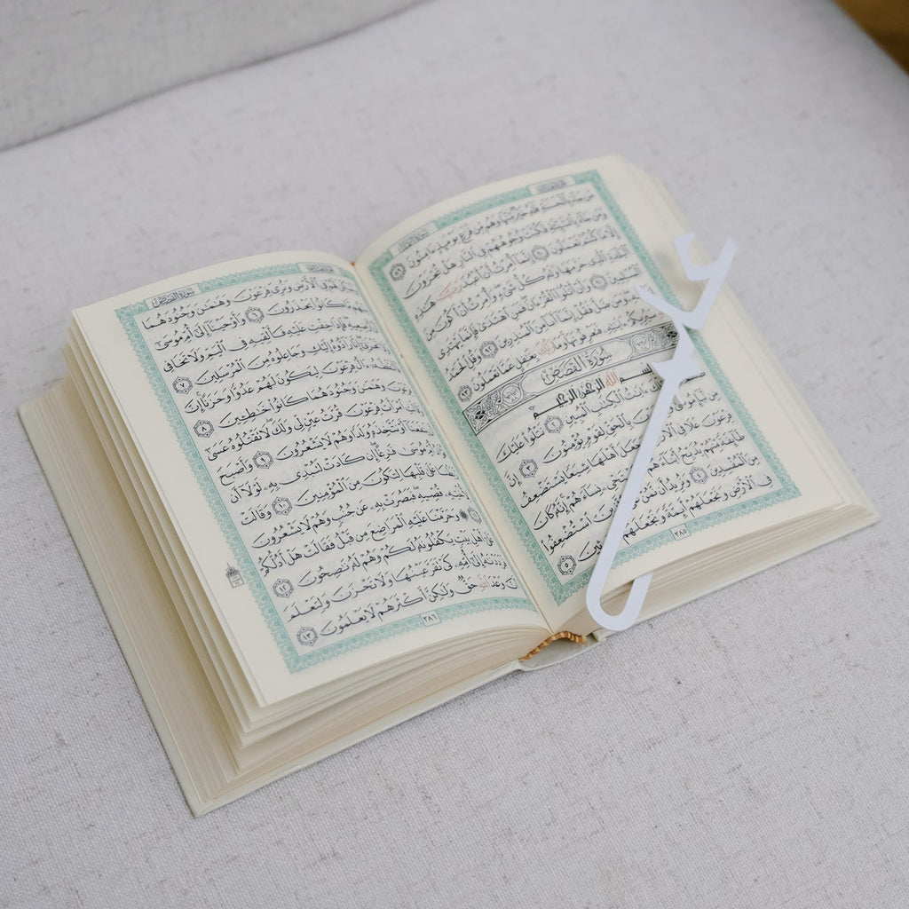 Open book on a chair with a wooden armrest. Quran bookmark