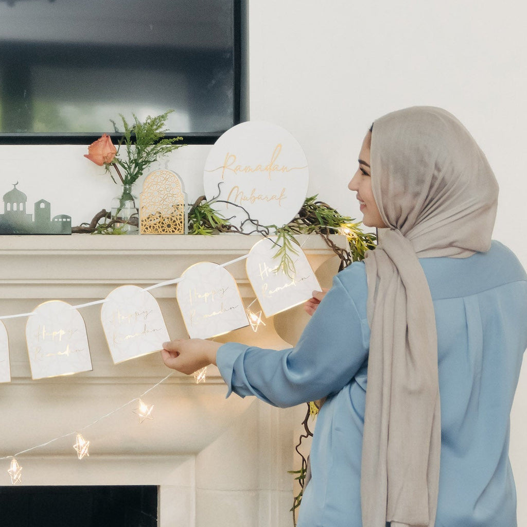 Two women decorating for Ramadan and eid. A fireplace with a banner in a living room. Ramadan Arches Banner; Ramadan Decorations; Party; Decor; Islamic Decor; Muslim Decor; Happy Ramadan; Jerusalem; Modern; Gold; Elegant; Arch Banner