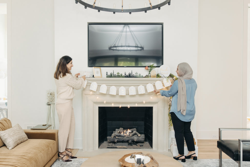 Two women decorating a fireplace in a living room with a TV above. Ramadan Arches Banner; Ramadan Decorations; Party; Decor; Islamic Decor; Muslim Decor; Happy Ramadan; Jerusalem; Modern; Gold; Elegant; Arch Banner